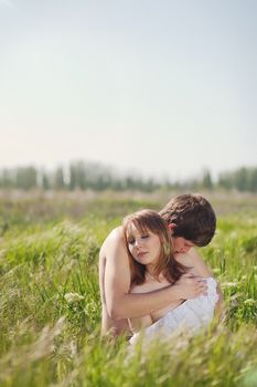 beautiful young pair kissing and hugging on green grass