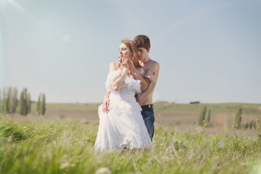beautiful young pair kissing and hugging on green grass