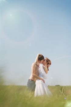 beautiful young pair kissing and hugging on green grass