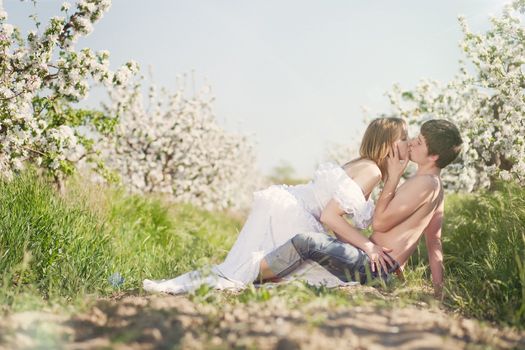 beautiful young couple kissing in the flowering gardens