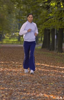 Young woman running in an autumn park.Shot with Canon 70-200mm f/2.8L IS USM