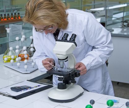 Female researcher working with a microscope in a laboratory.