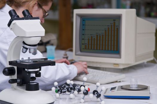 A female researcher analyzing some data at her lab desk.The image on the computer screen is mine.Selective focus on the microscope.