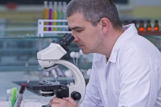 Male researcher looking through a microscope in a laboratory.Shot with Canon 70-200mm f/2.8L IS USM