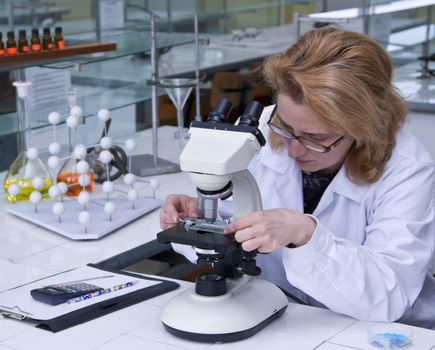 Female researcher fixing a spangle on a microscope.
