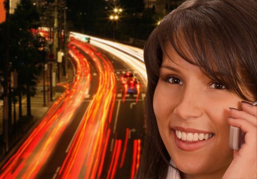 Close-up of a young businesswoman using a mobile phone in a city street at night.        
