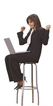 Businesswoman expressing satisfaction in front of a laptop while she is sitting on a high chair.