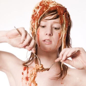 Portrait of a young girl eating spaghetti of her head concentrating