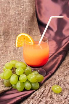 a picture of an orange cocktail with a branch of grape