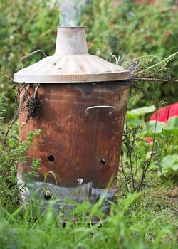 A garden incinerator burning plant waste on an English allotment
