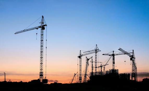 Silhouettes of tower cranes on a background of a decline