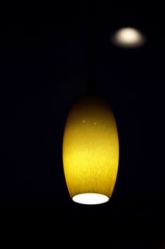 A simple stylish amber colored hanging ceiling light in a dark background 