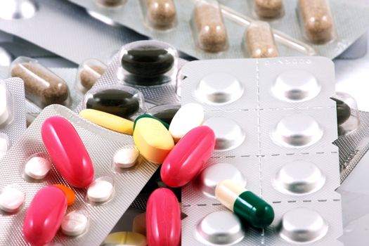 Pills of many shapes and colors grouped together