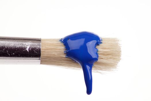 paint brush dripping with different coloured paints