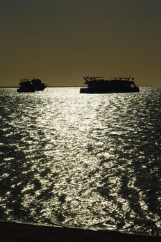 silhouettes of yachts in the ocean at sunset
