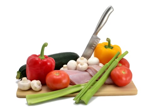 chicken, knife and vegetables on a cutting board, isolated on white