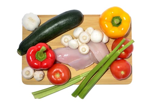 chicken, knife and vegetables on a cutting board, isolated on white