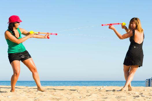 Girls with water pistols fooling around on the beach