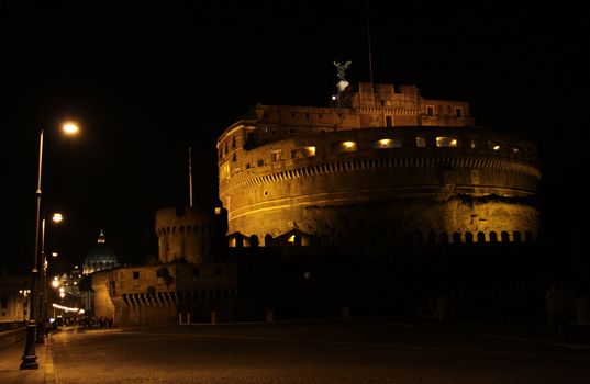 The towering Castel Sant'Angelo (Mausoleum of Hadrian) in Rome, Italy.  Shot at night with St. Peter's  Basilica in the background.
