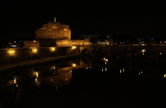The towering Castel Sant'Angelo (Mausoleum of Hadrian) in Rome, Italy.  Shot at night from across the Tiber river.
