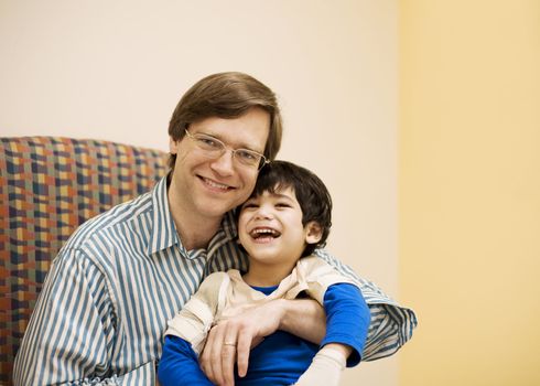 Father holding disabled son in doctor's office