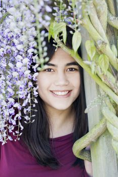Beautiful young woman or teen girl standing under wisteria vines