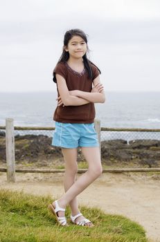 Little nine year old girl posing arms crossed by ocean