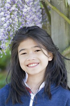 Beautiful young nine year old  girl standing under wisteria vines