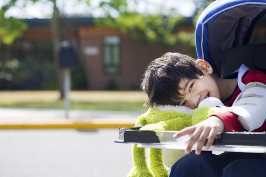 Disabled five year old boy in wheelchair in front of school