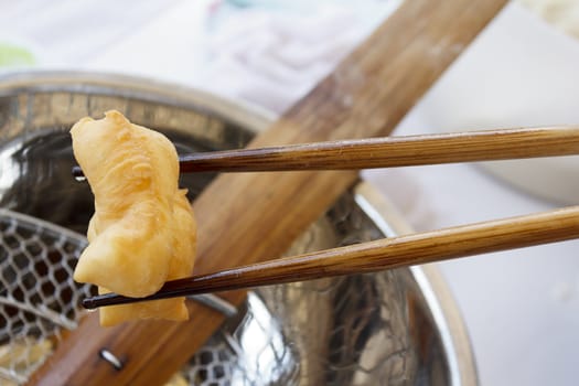 Bamboo chopsticks holding deep-fried dough stick, Chinese doughnut, breakfast or snack of the chinese people