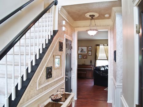 Inviting entranceway in an expensive modern American home. A sofa, piano and window in the living room are visible in the backgound.