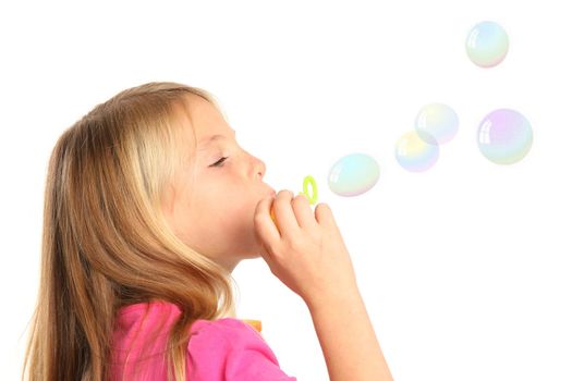 Little girl with blond hair blowing soap bubbles