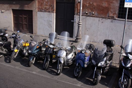 A line of parked motor bikes in Rome, Italy.