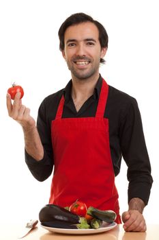 a chef with a plate of vegetables in front of him holding a tomatoe