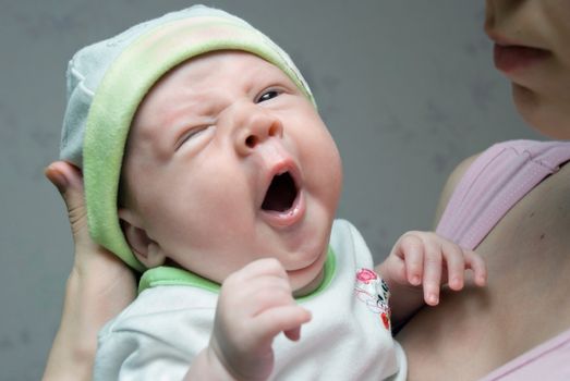Yawning little baby in his mom arms