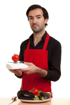 a chef weighing a tomatoe with a kitchen scale