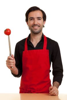 a chef showing a tomatoe pierced with the tip of a kitchen knife