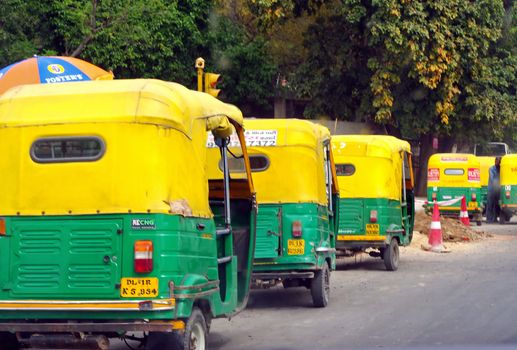 Auto rickshaws in a line on a street in New Delhi, India. These iconic taxis have recently been fitted with CNG powered engines in an effort to reduce pollution.
