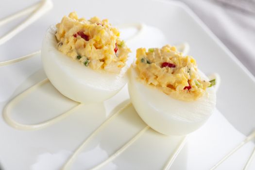 Two gourmet deviled eggs on white plate