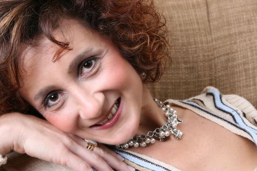 Mature female, lying on a sofa, wearing beautiful jewelery