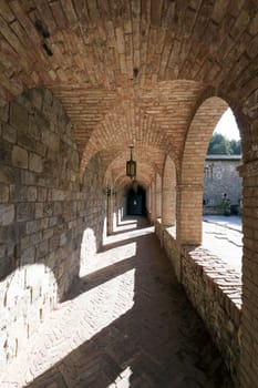 A stone corridor leading one around a courtyard