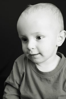Sepia toned image of a little toddler boy on black background