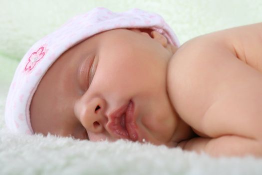 Beautiful newborn baby girl sleeping on a fluffy blanket 