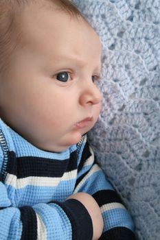 Two month old baby boy lying on a knitted blanket