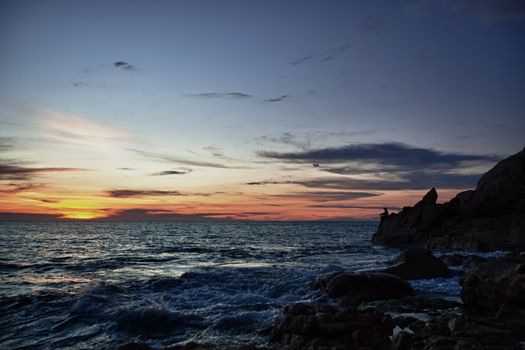 Evening on the beach. Sunset, rocks and fisherman