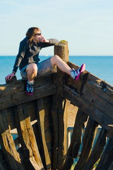 Teenager sitting on the prow of a shipwreck, a concept