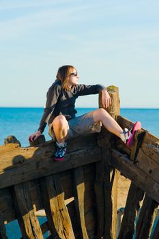 Teenager sitting on the prow of a shipwreck, a concept