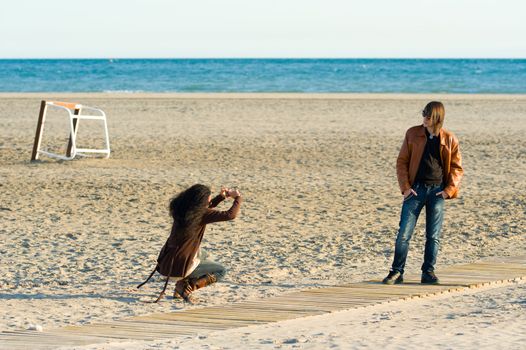 Woman taking photographs of a teenager on the beach