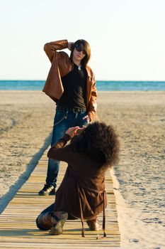 Woman taking photographs of a teenager on the beach