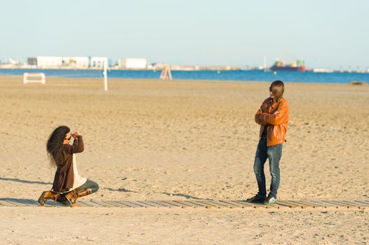 Woman taking photographs of a teenager on the beach